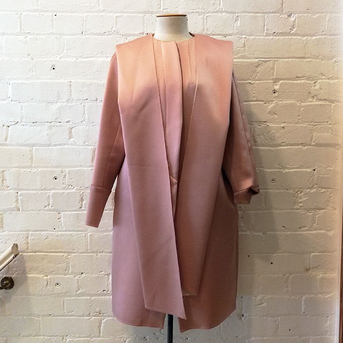 Collarless opera coat with pockets and deconstructed edges.